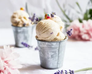 A bowl of creamy Honey Lavender Ice Cream with lavender flowers and honey drizzle.