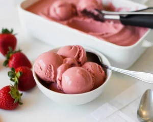 Homemade low-fat strawberry frozen yogurt in a bowl topped with fresh strawberries.