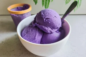 A bowl of creamy ube ice cream topped with sprinkles and vibrant purple hues.