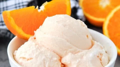 Bowl of homemade orange ice cream with orange slices on top