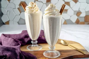 Ninja Eggnog Slushy in a festive cup, topped with whipped cream and nutmeg.