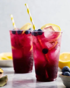 A refreshing glass of Blueberry Lemon Soda with berries and lemon slices.